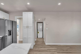 A kitchen with white cabinets and a refrigerator.