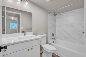 A white bathroom with a marble wall and a white toilet.