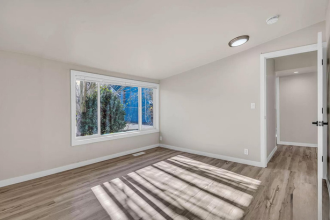 A room with a large window and wooden flooring.