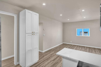 A white cabinet is in a room with a wooden floor.