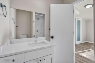 A white bathroom with a sink, mirror, and cabinet.