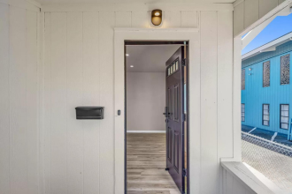 A white hallway with a brown door and a mailbox on the wall.