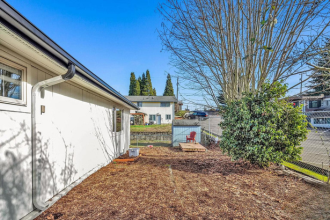 A white house with a brown dirt area in front.