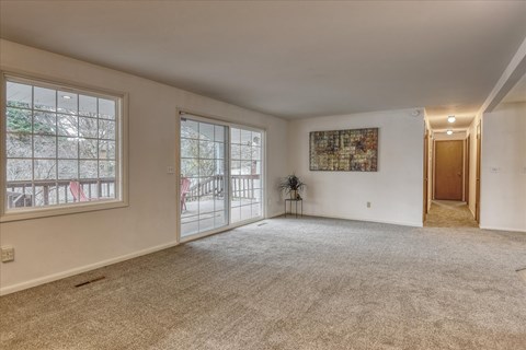 A spacious room with a carpeted floor and a large window.