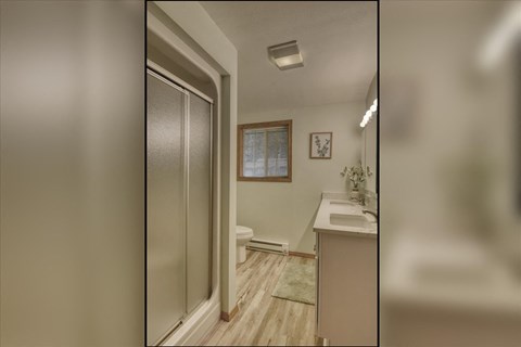A bathroom with a toilet, sink, and a window.