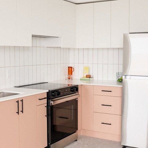A kitchen with pink cabinets and a white fridge.