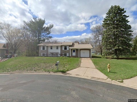 A house with a driveway and a yellow fire hydrant in front.