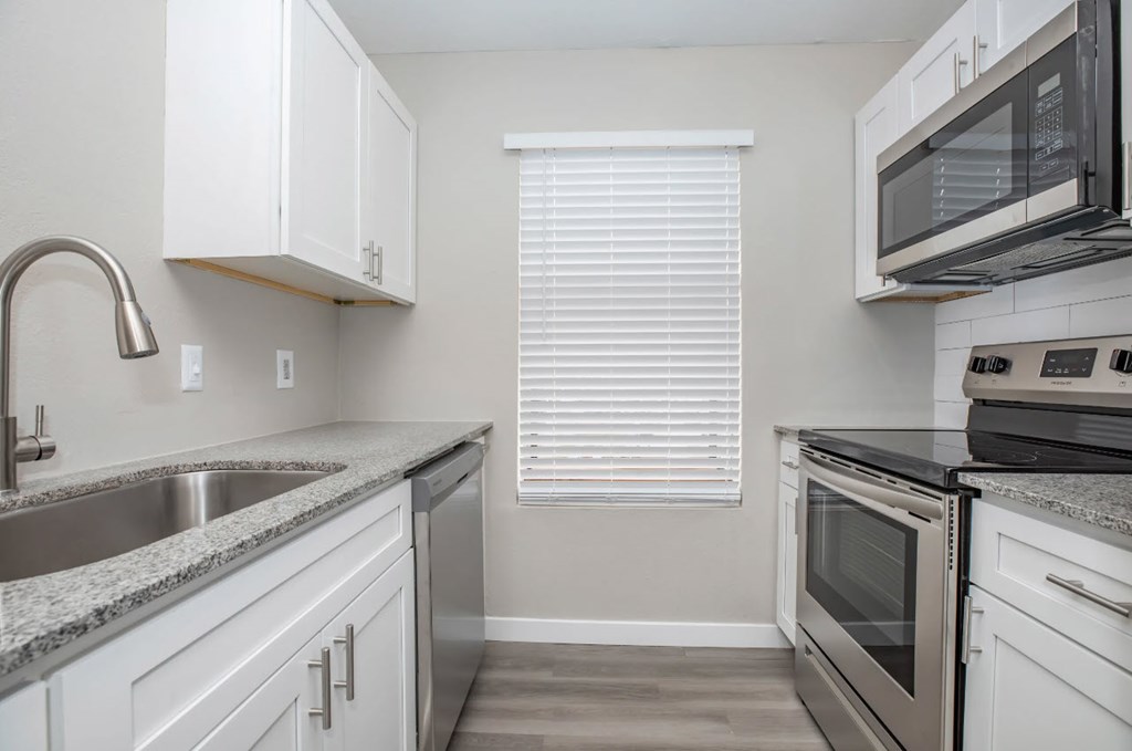 A kitchen with white cabinets and a stainless steel sink.