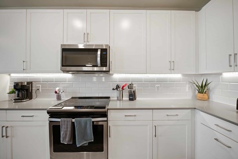 A modern kitchen with white cabinets and a black stove top.