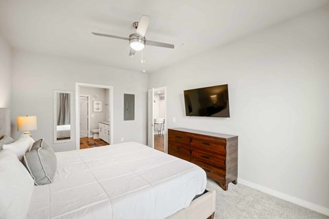 A bedroom with a large bed and a flat screen TV mounted on the wall.