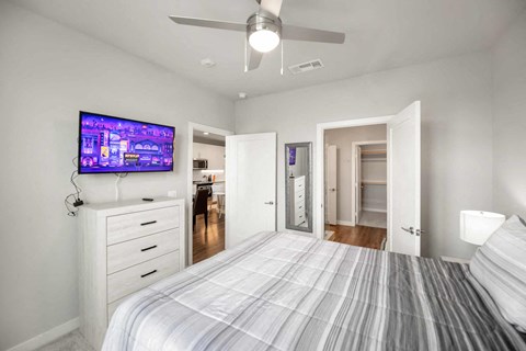 A bedroom with a bed, dresser, and television.