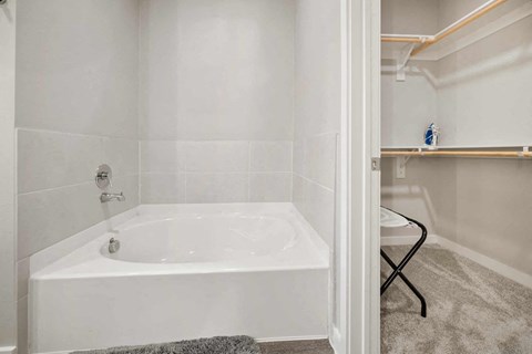 A white bathroom with a bathtub and a chair.