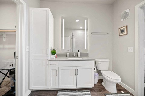 A white bathroom with a toilet, sink, and mirror.