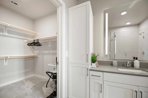 A white bathroom with a sink, mirror, and a chair.