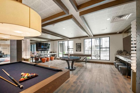 A pool table is in the middle of a room with a bar and a TV.