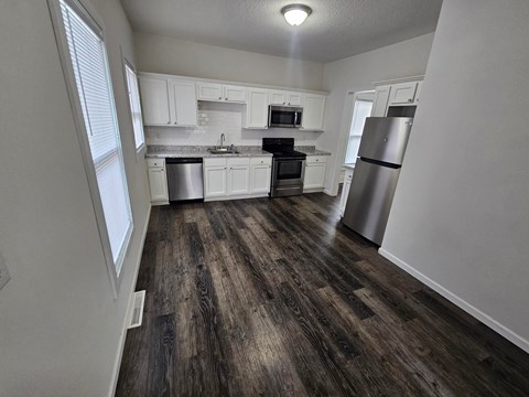A kitchen with white cabinets and a wooden floor.