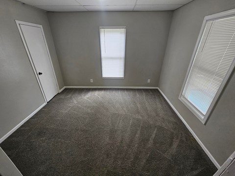 A room with a carpeted floor and a window with blinds.