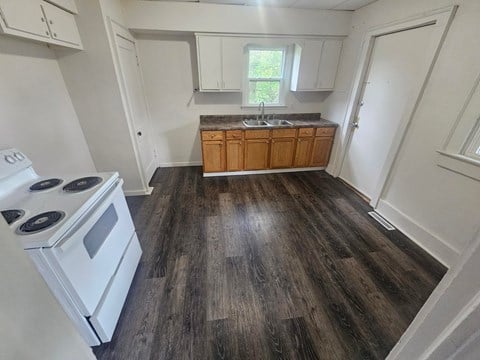 A kitchen with a white stove and wooden cabinets.