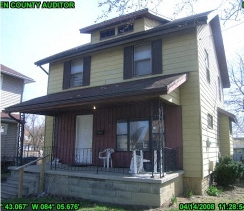 A yellow house with a porch and a white chair.