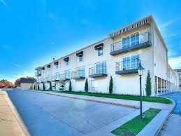 A row of white apartment buildings with balconies and green lawns.
