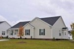 A white house with a black roof and a grey lawn.