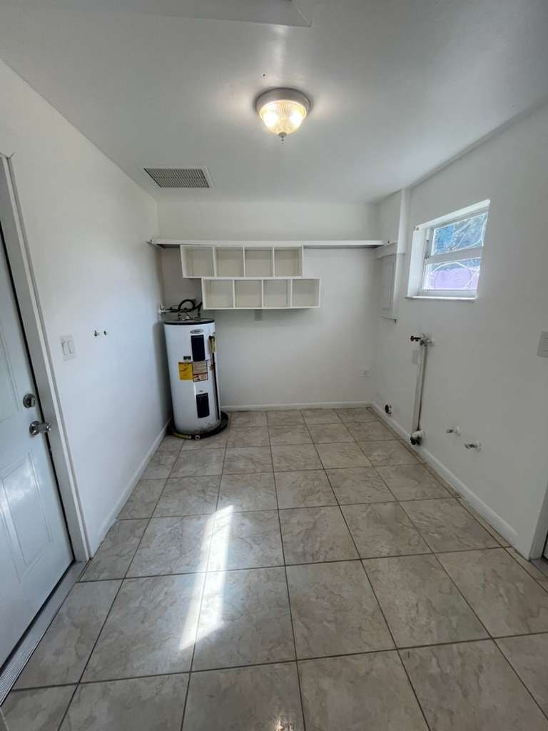 A white room with a tiled floor and a small kitchenette.