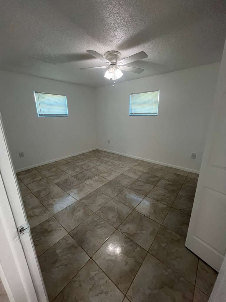 A room with tile flooring and two windows.