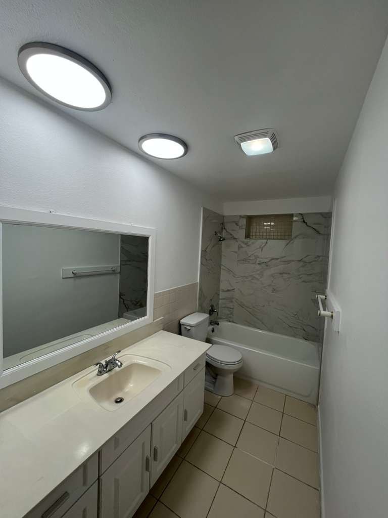 A bathroom with a sink, toilet, and mirror.