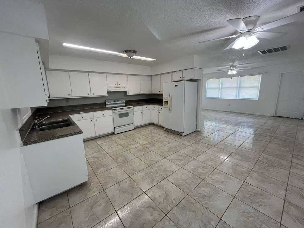 A kitchen with white cabinets and a tile floor.