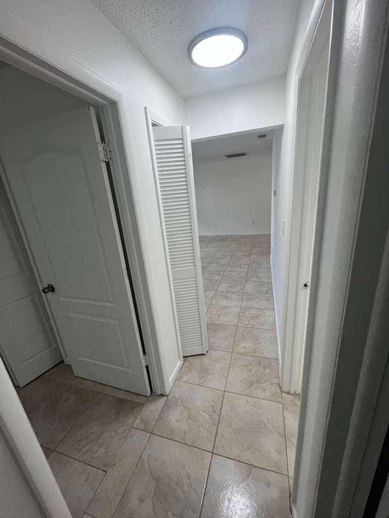 A white hallway with a door on the left and a closet on the right.