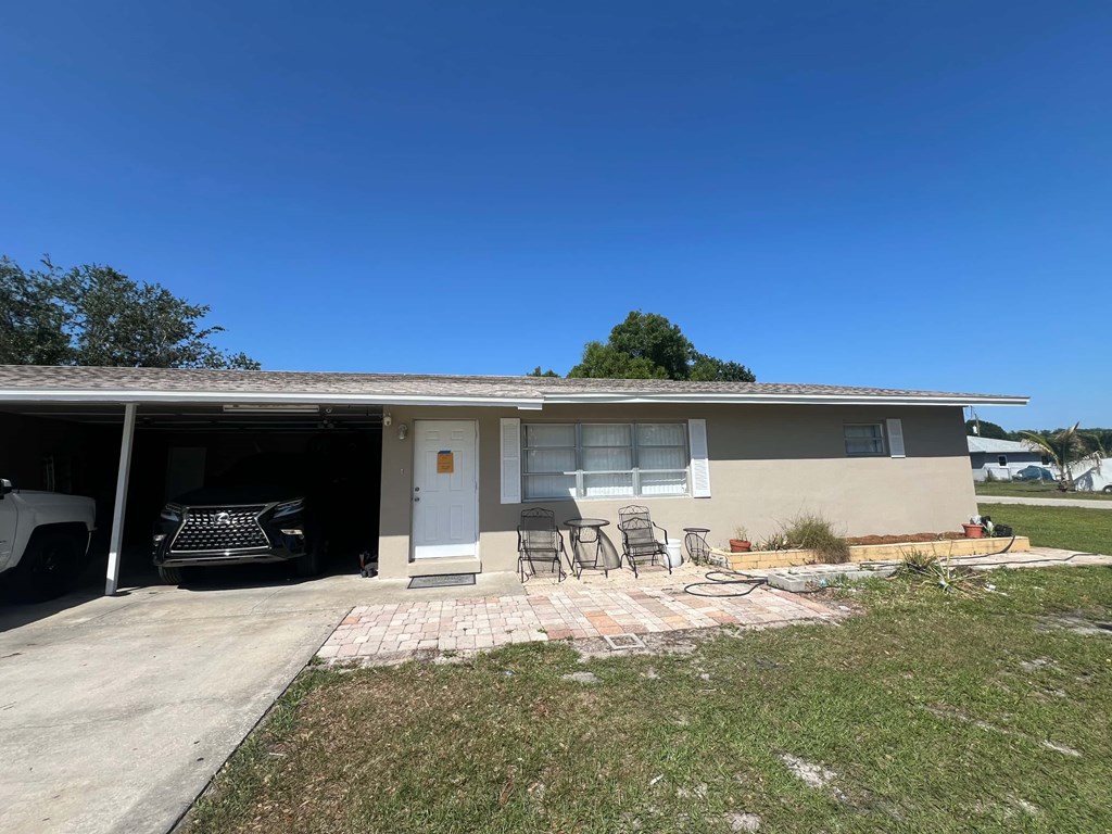 A house with a white door and a garage with a black car in it.