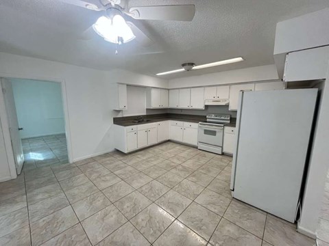 A kitchen with white cabinets and a white refrigerator.