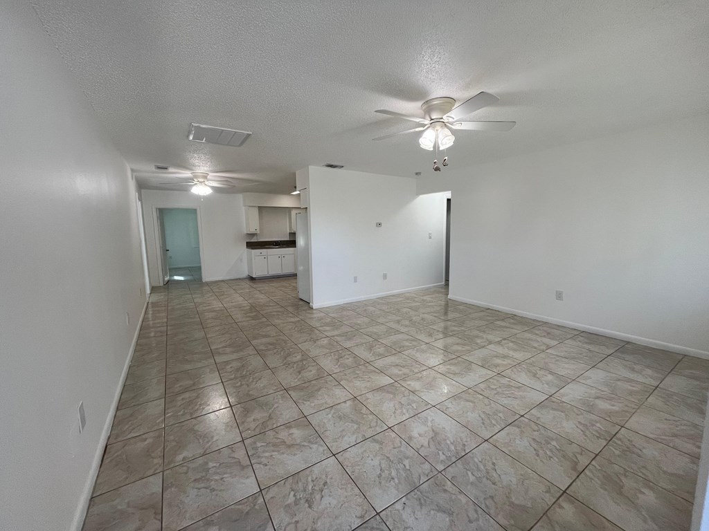 A spacious room with a ceiling fan and tile flooring.