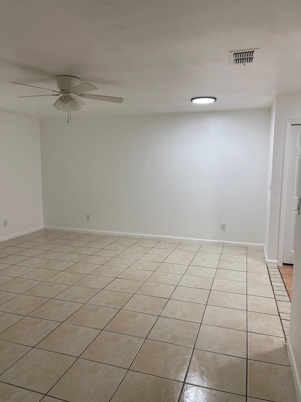 A room with a ceiling fan and tile flooring.