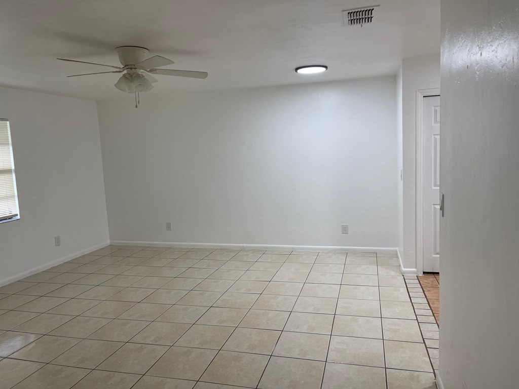A room with a ceiling fan and tile flooring.