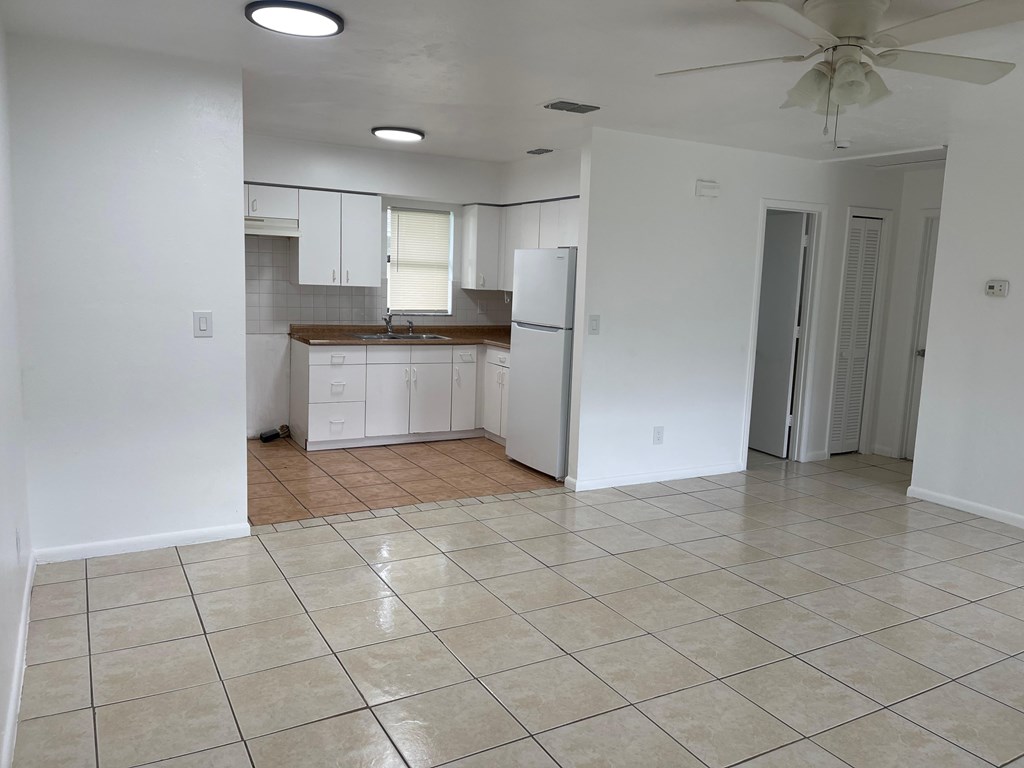 A kitchen with white cabinets and a fan on the ceiling.