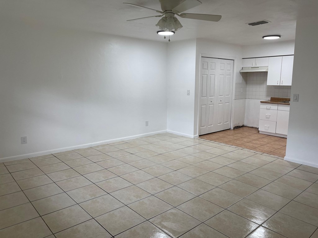 A room with a ceiling fan and tile flooring.