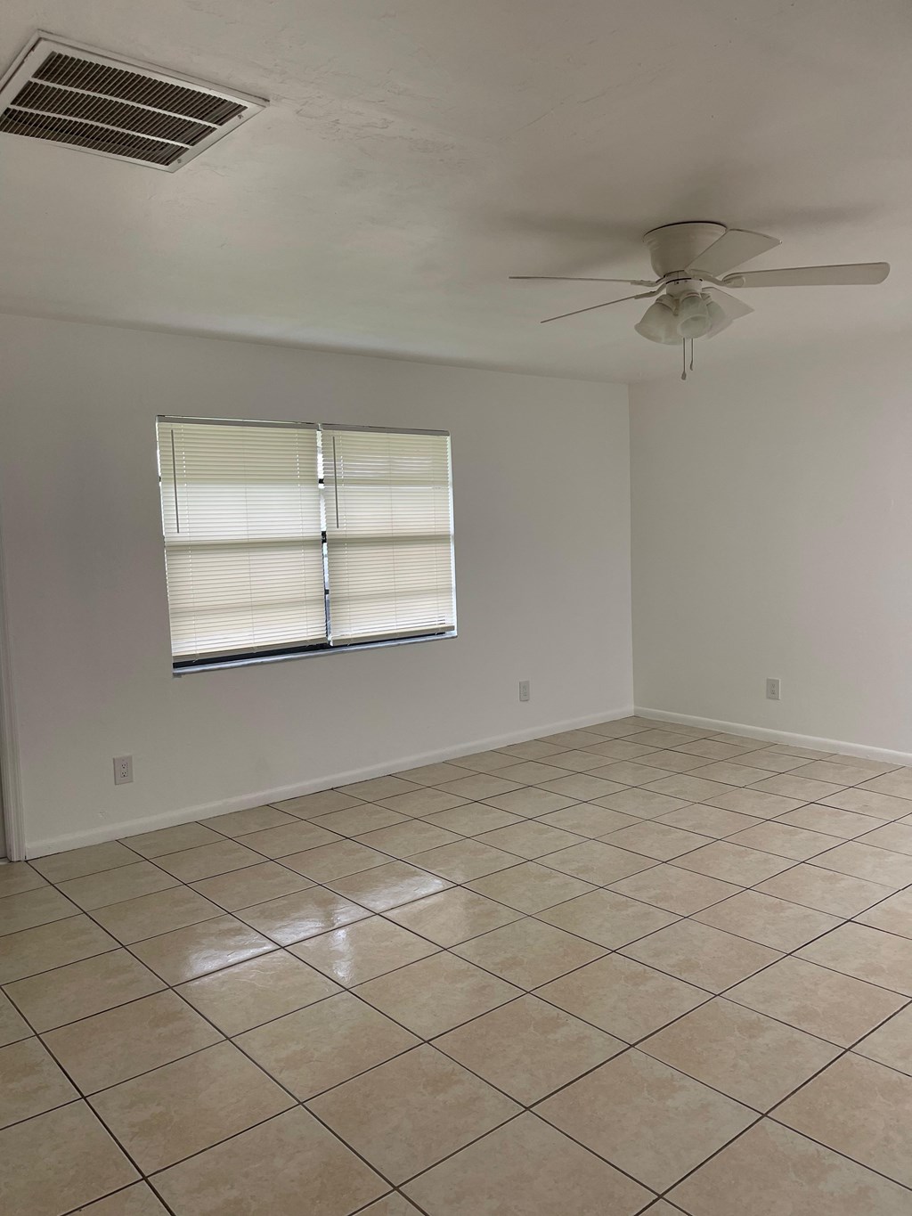 A room with a ceiling fan and a window with blinds.