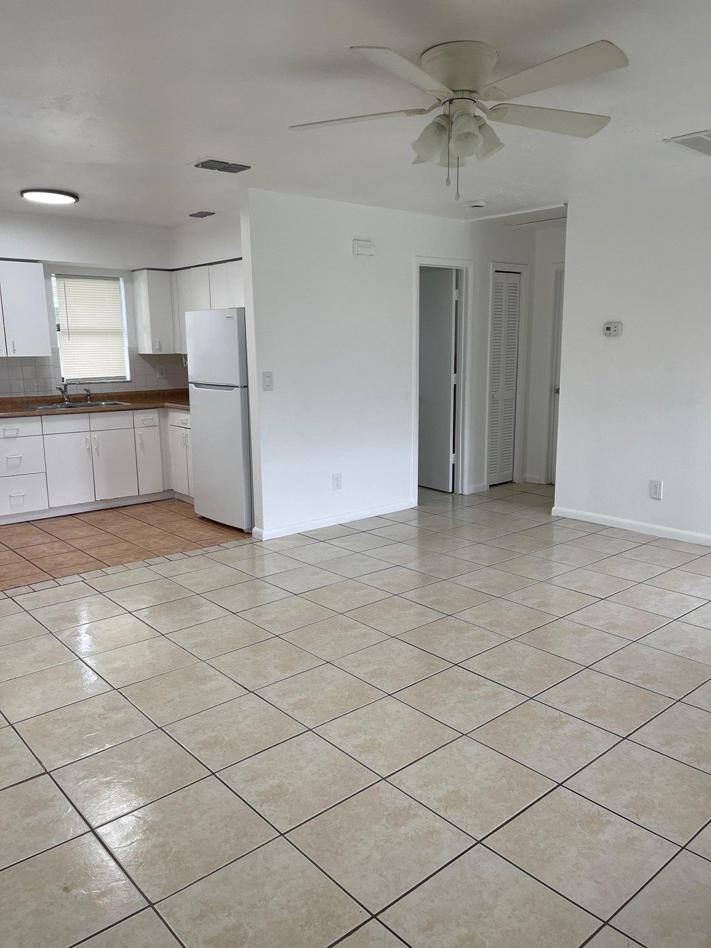 A kitchen with white cabinets and a tiled floor.