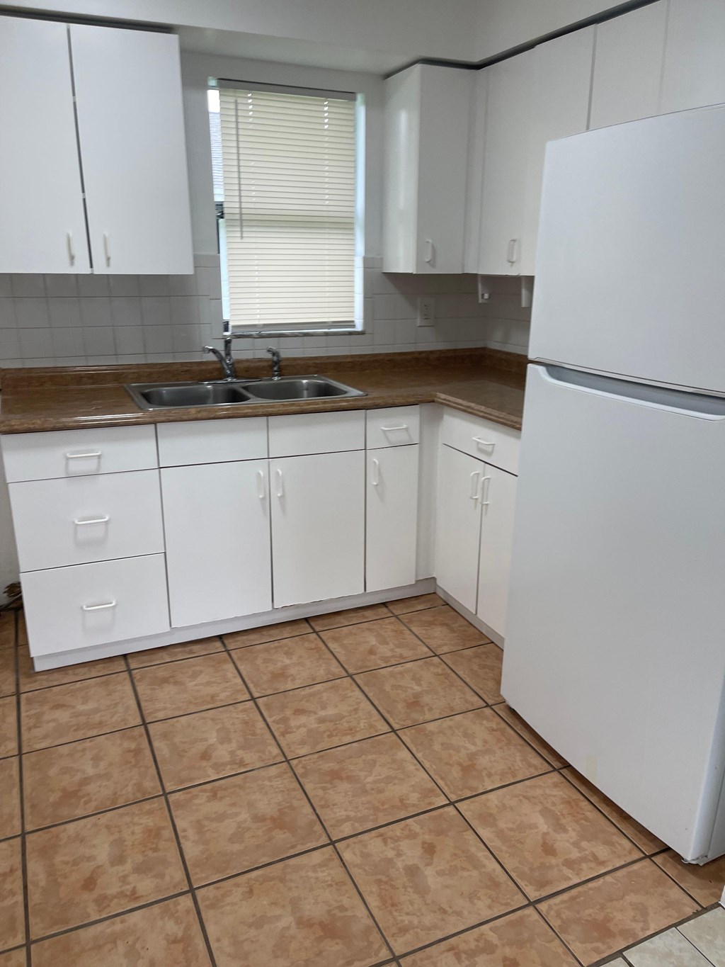 A kitchen with white cabinets and a white refrigerator.