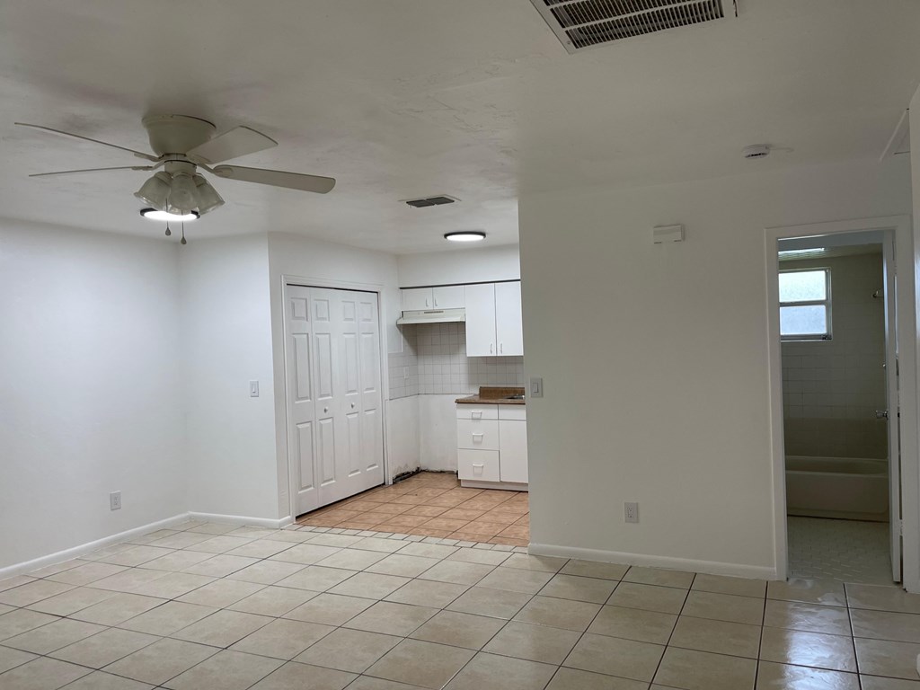 A room with a ceiling fan and tiled floor.