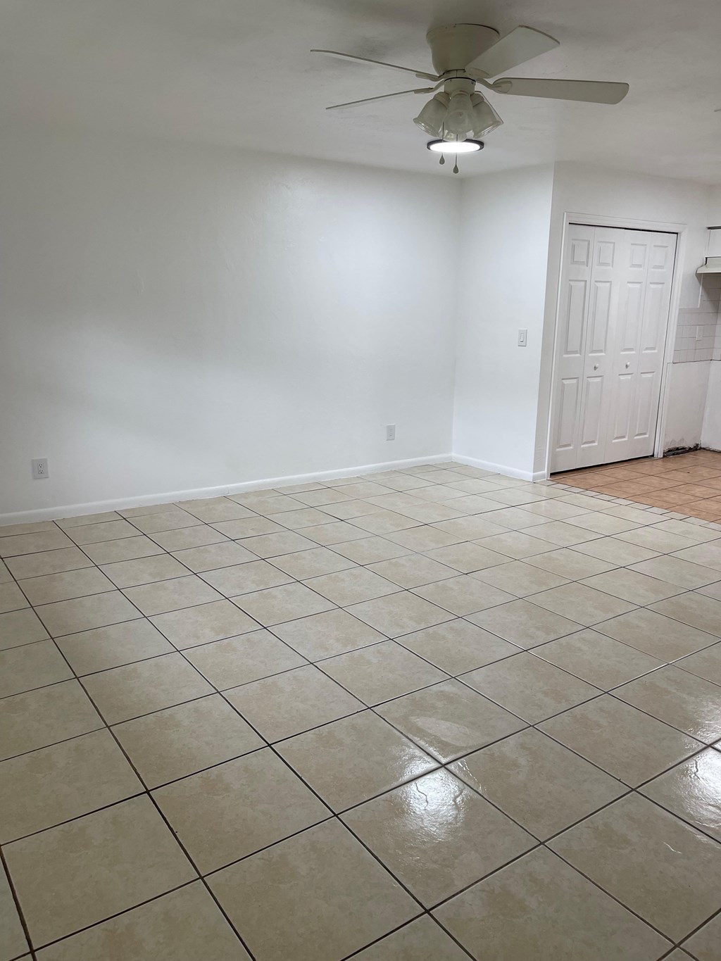 A room with a ceiling fan and tile flooring.