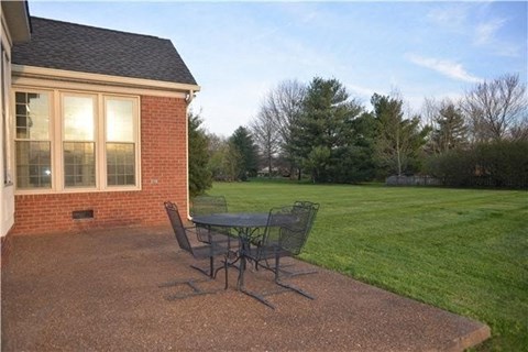 A patio with a table and chairs is in front of a house.