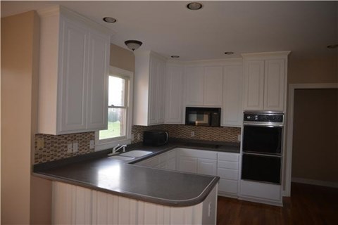A kitchen with white cabinets and a black countertop.
