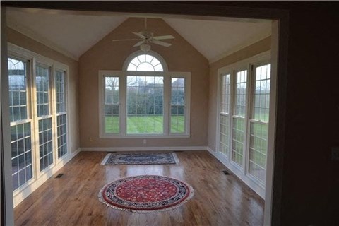 A room with a ceiling fan and a rug on the floor.