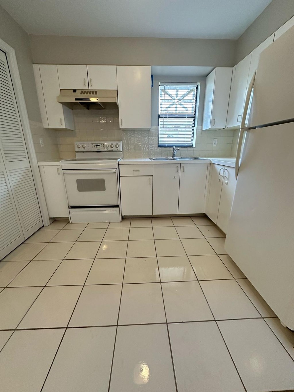 A kitchen with white appliances and cabinets.