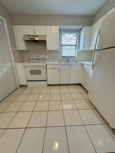 A kitchen with white appliances and cabinets.