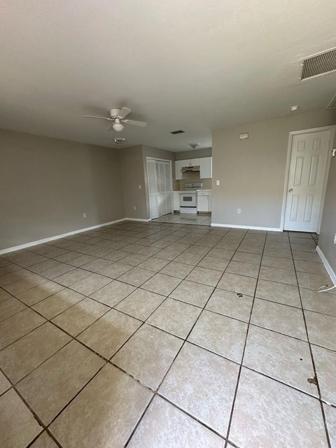 A spacious room with tile flooring and a ceiling fan.