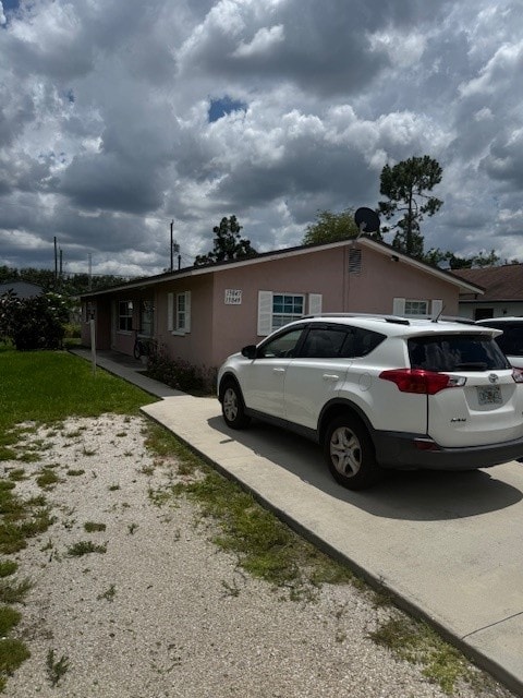 A white car is parked in front of a pink house.