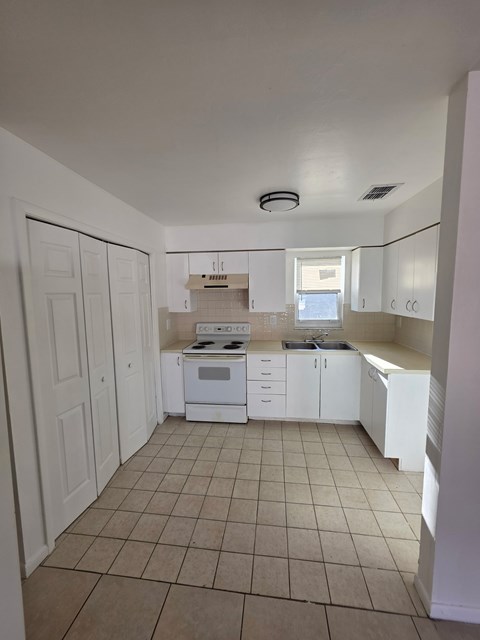 A kitchen with white cabinets and a tiled floor.